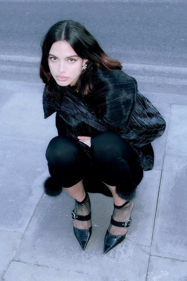 Woman in black pleated top and pants with pointed heels